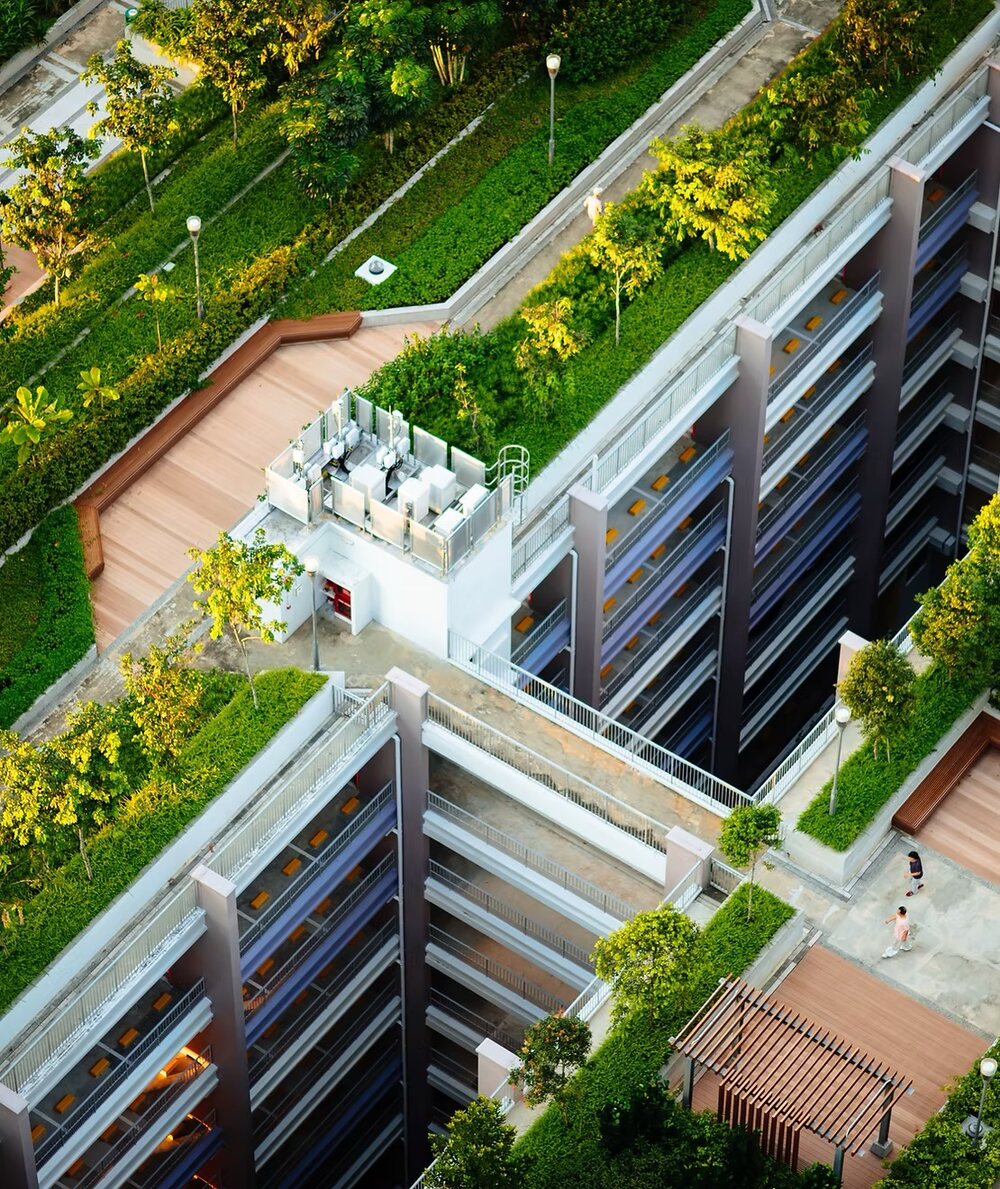 Aerial view of a green-terraced building with planted balconies and rooftop equipment.